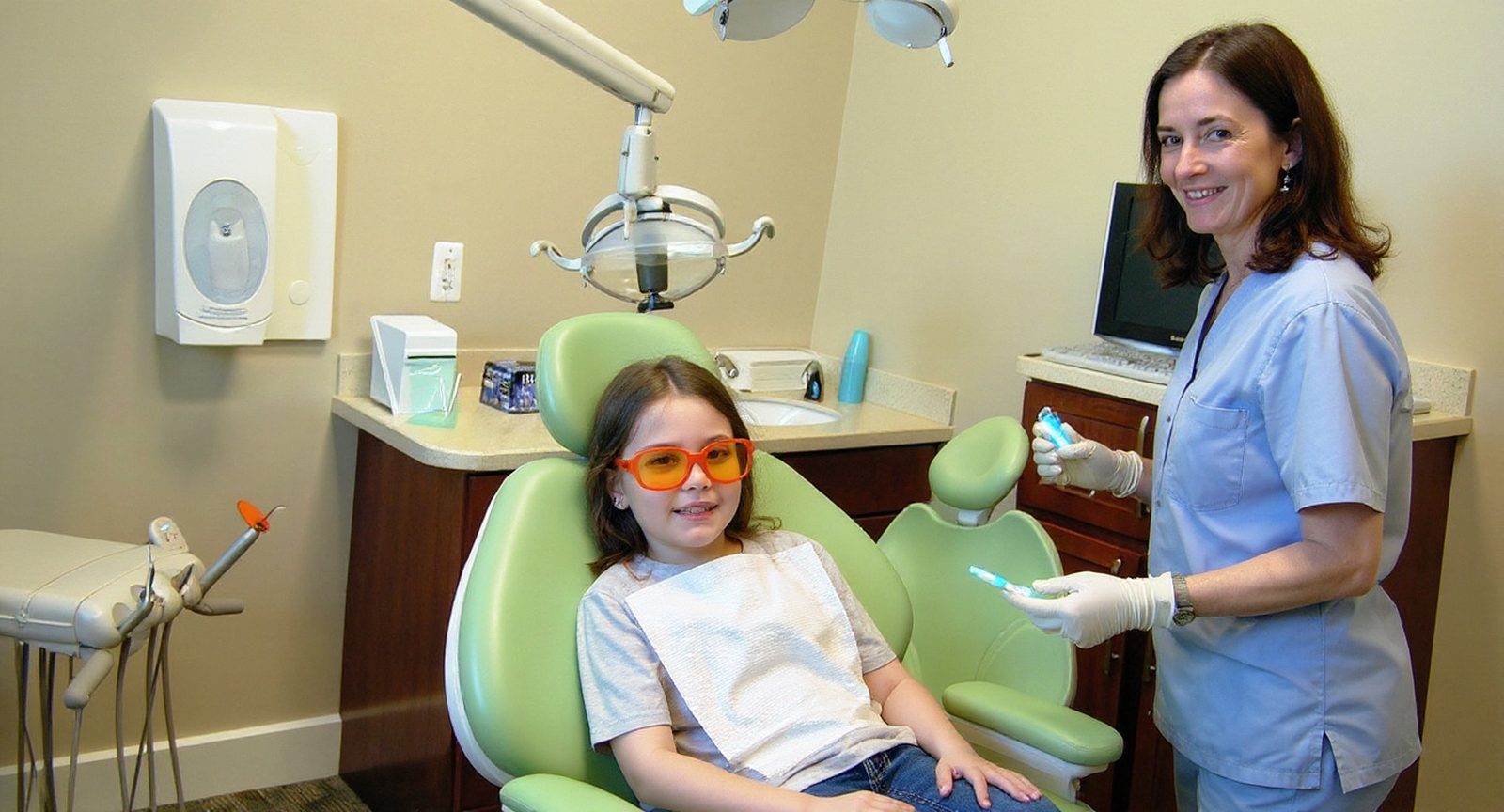 A girl in protective glasses while a pediatric dentist applies sealants at Lakes Pediatric Dentistry